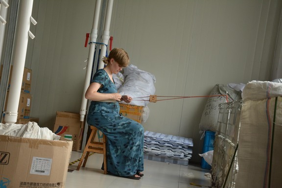 Anne Knutsen vever inne i en maskinhall. Foto: Feng Zhen Kun.